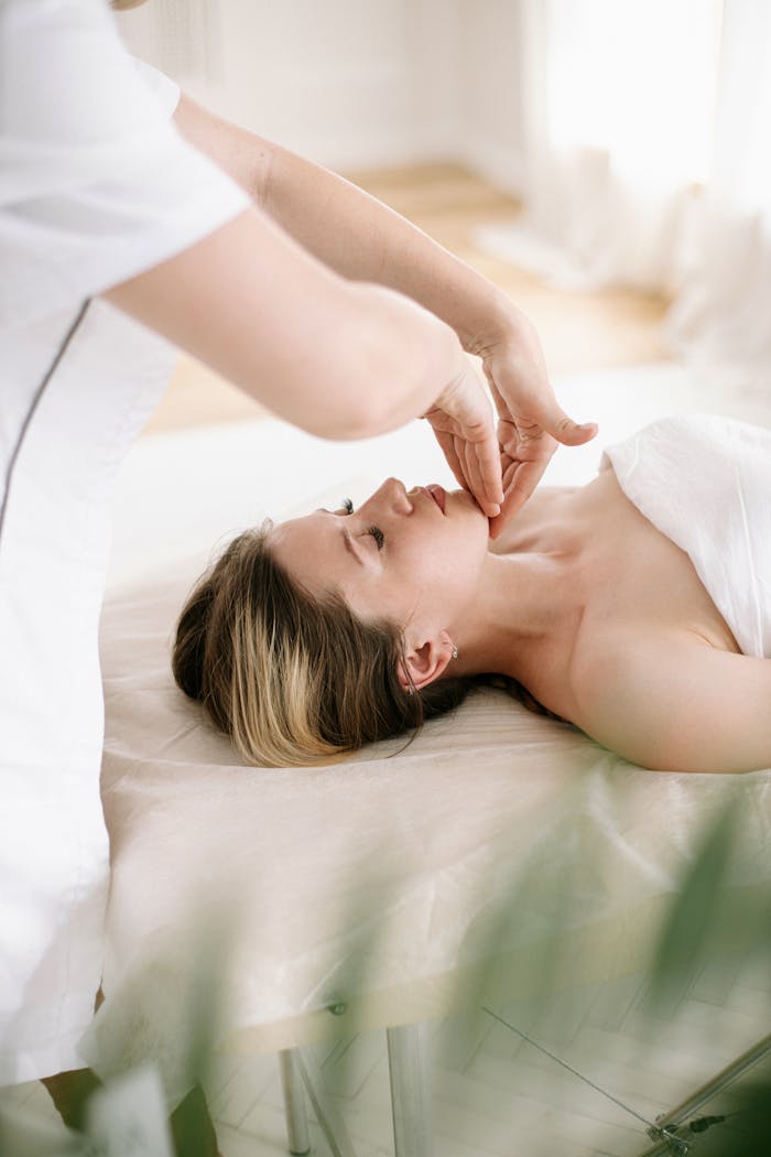 Woman enjoys a soothing facial massage in a serene spa environment, promoting relaxation and skincare.