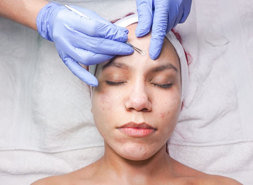 Woman undergoing professional facial treatment with eyes closed and gloves.